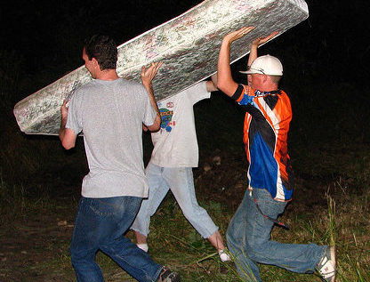 a group of men carrying a mattress