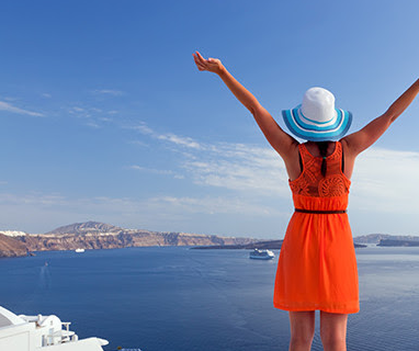 a woman in an orange dress and hat with her arms raised over water