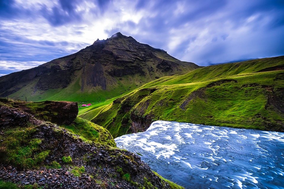 a river flowing through a valley with Quiraing in the background