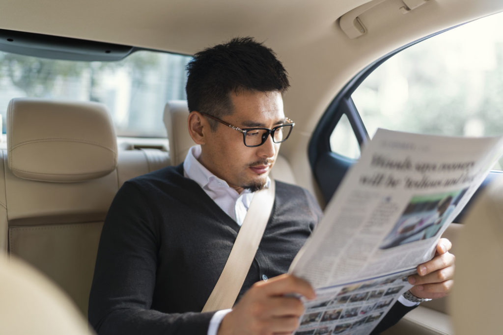 a man reading a newspaper in a car