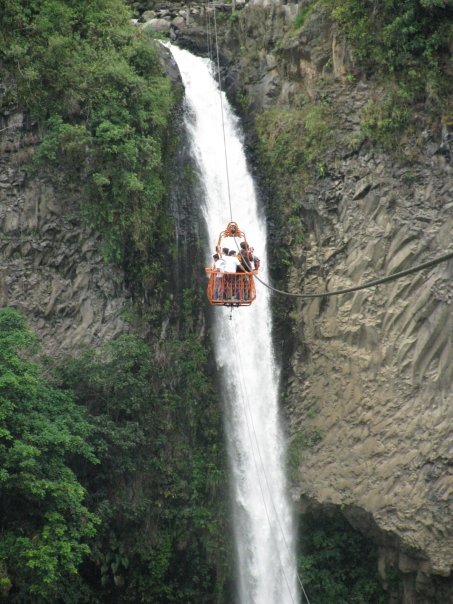 a group of people on a rope in a basket above a waterfall
