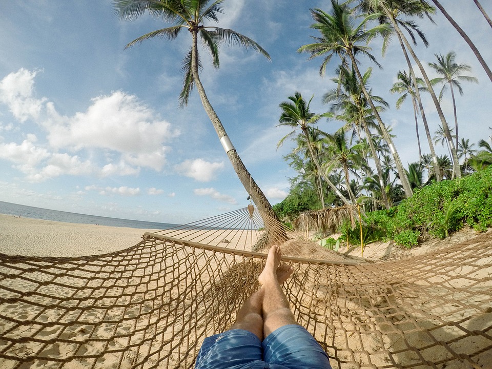 a person lying in a hammock on a beach