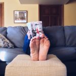 a person reading a magazine on a couch