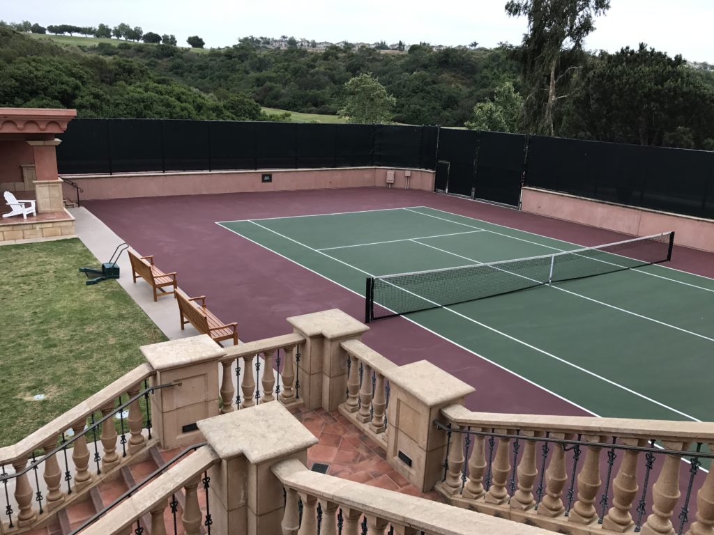 a tennis court with a fence and trees in the background