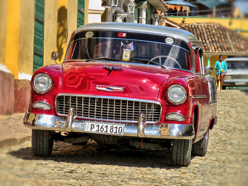 a red car parked on a cobblestone street