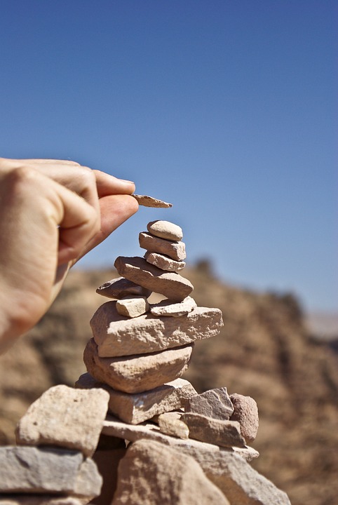 a person placing a rock on top of a stack of rocks