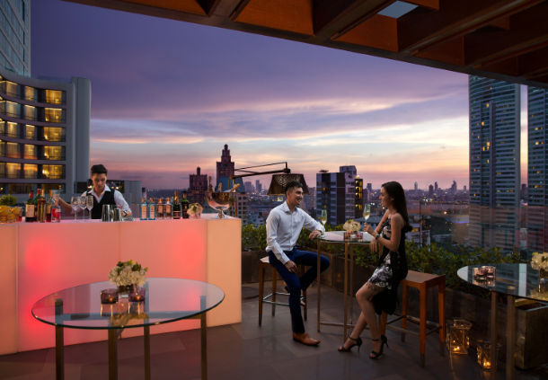 a group of people sitting at a table with drinks and a city view