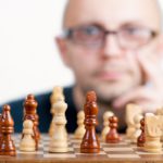 a man in glasses looking at chess pieces