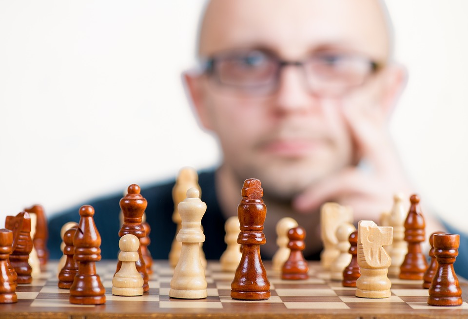 a man in glasses looking at chess pieces