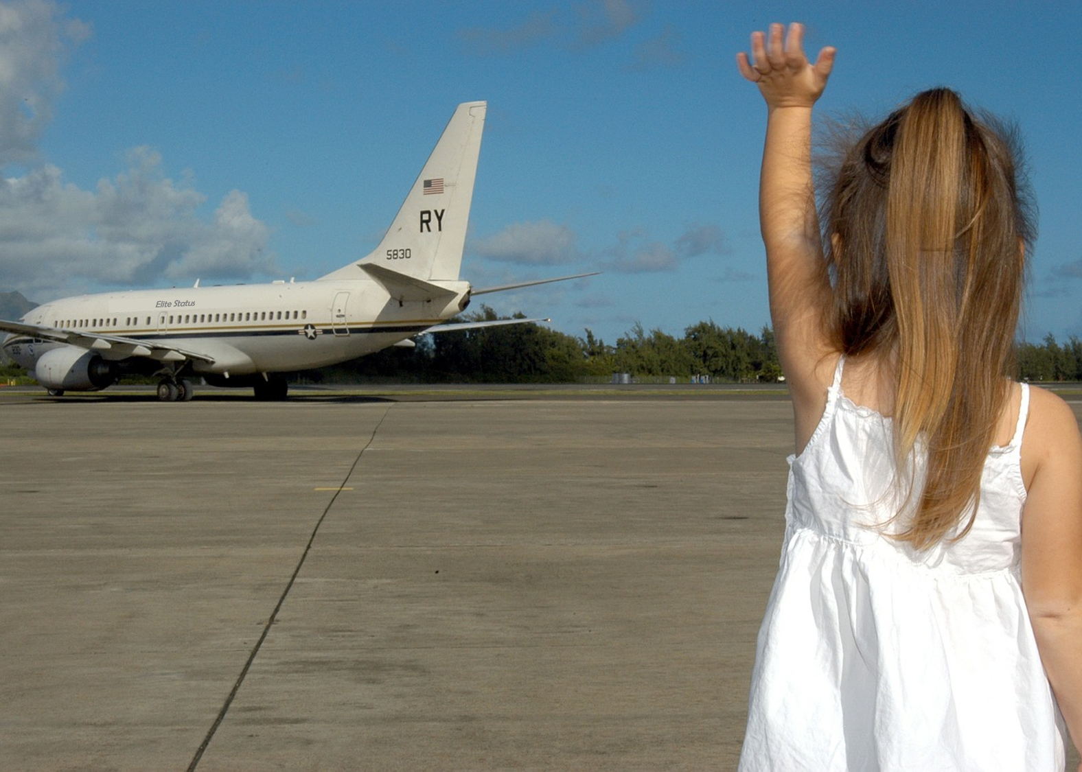 a girl raising her hand in front of an airplane