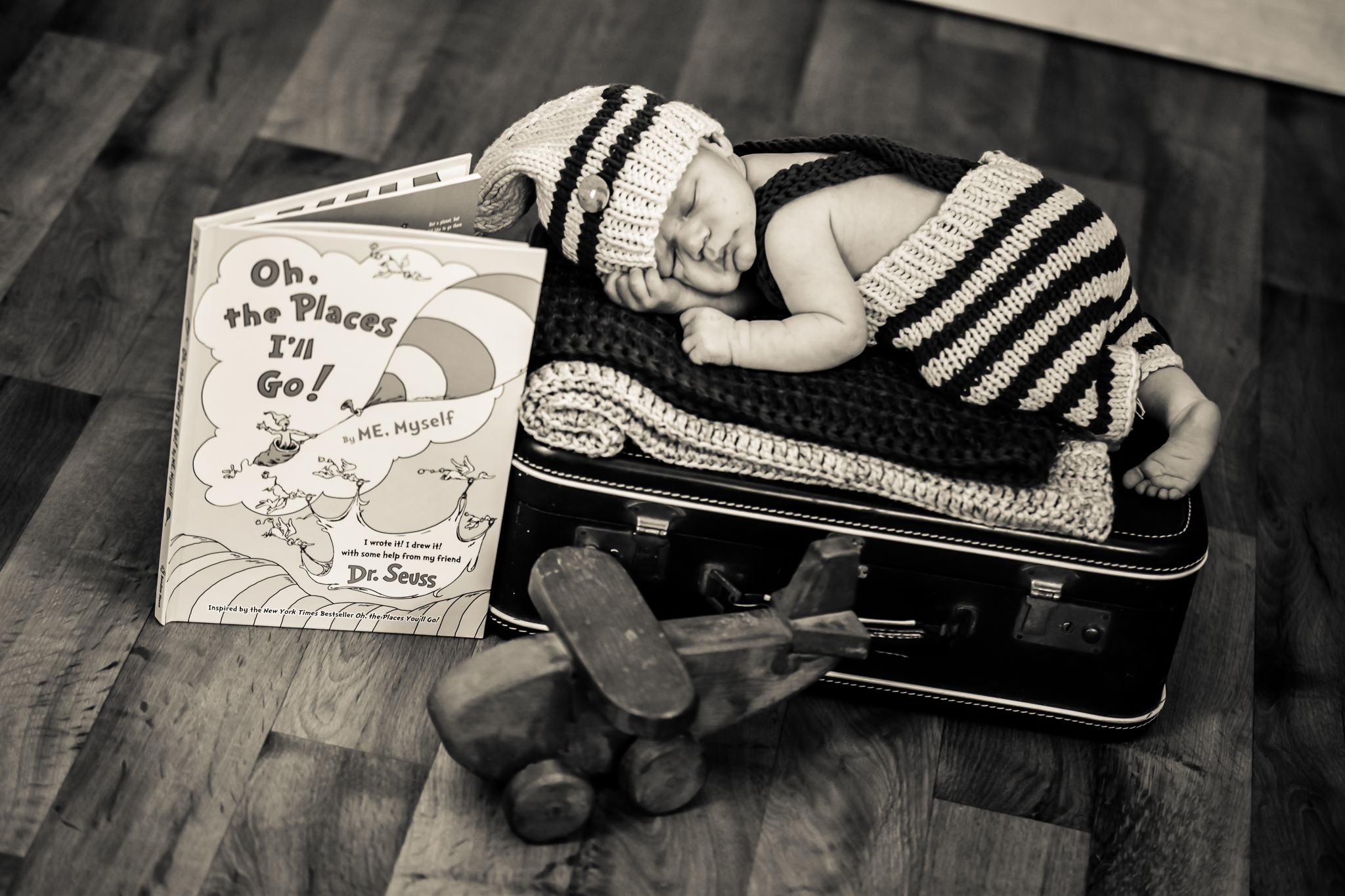a baby sleeping on a suitcase next to a book