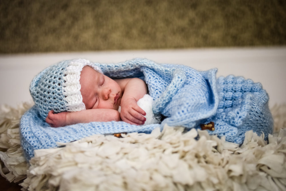 a baby sleeping in a blue and white knitted hat