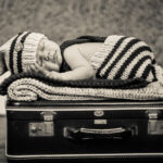 a baby sleeping on a suitcase