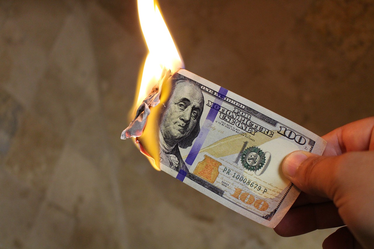 a hand holding a paper money on fire