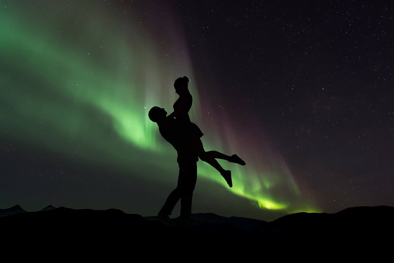 a silhouette of a man holding a woman in the sky