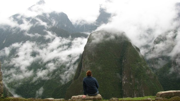 a person sitting on a rock looking at the mountains