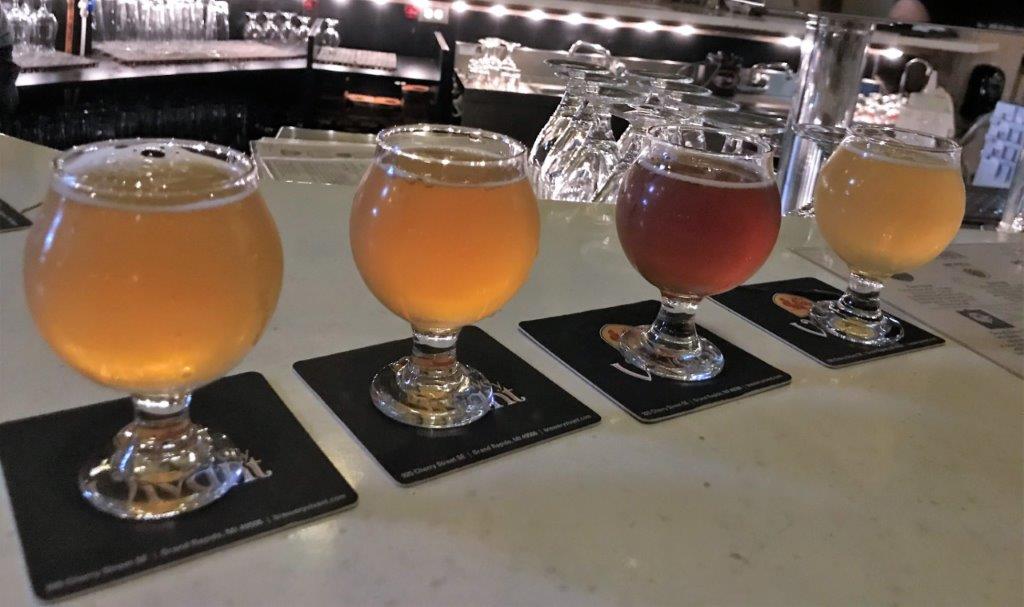 a row of glasses of beer on coasters