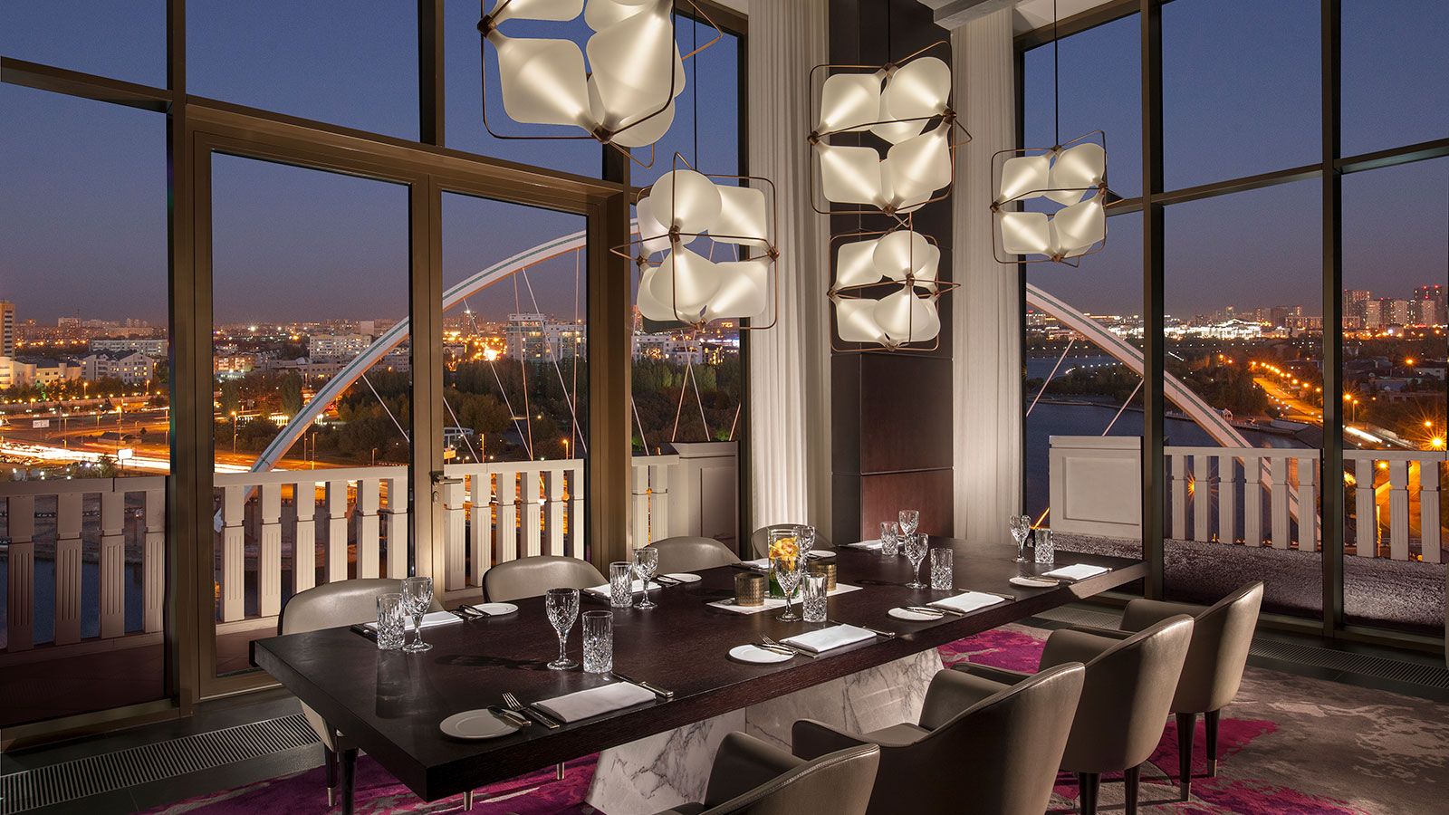 a table with chairs and plates in a room with a view of a city