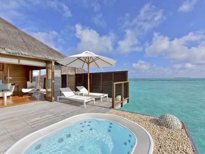 a pool and a hut with a hot tub on the water