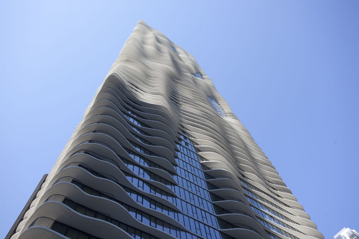 a tall building with curved balconies with Aqua in the background