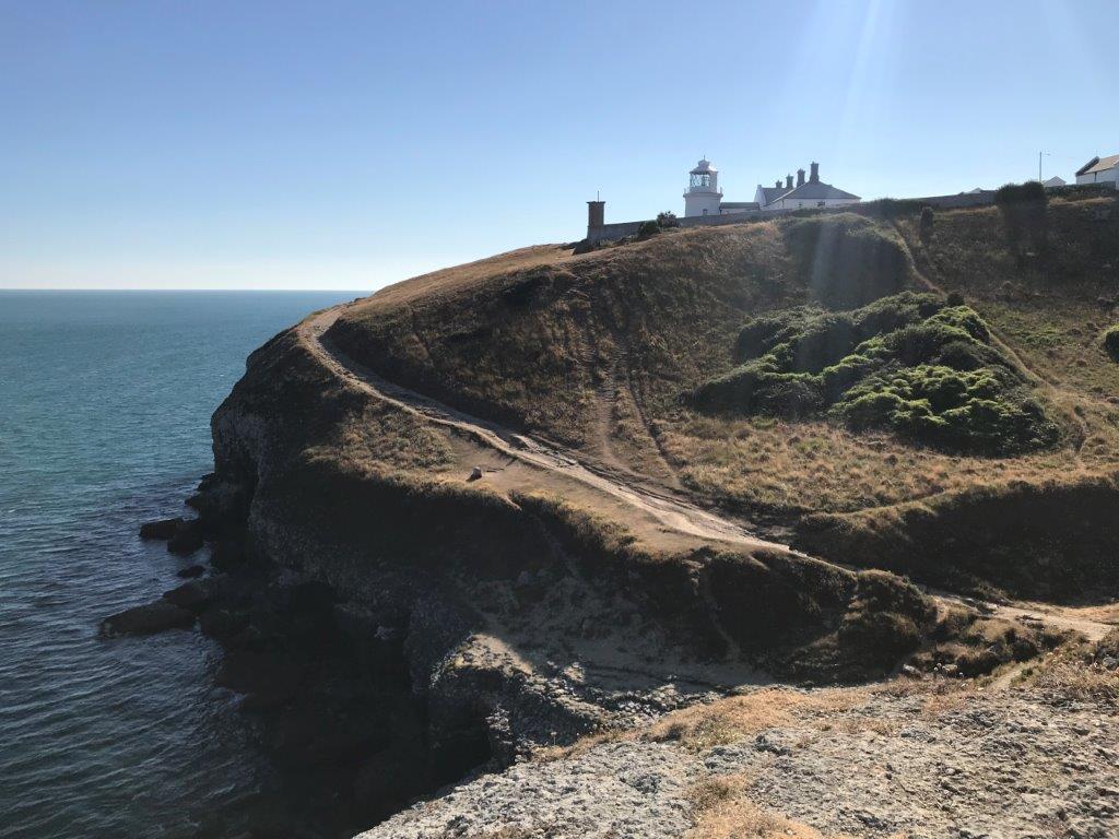 a path on a hill with a lighthouse on the top