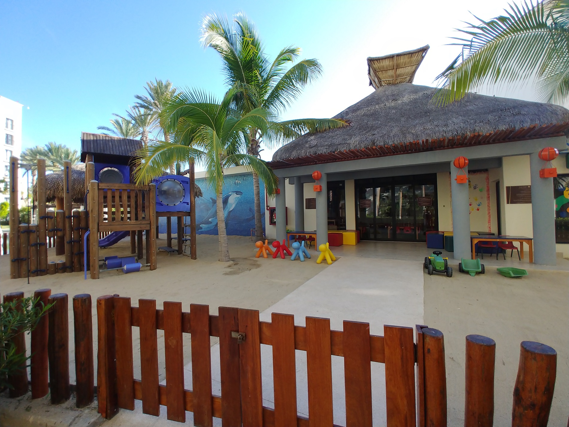 a playground with a fence and palm trees