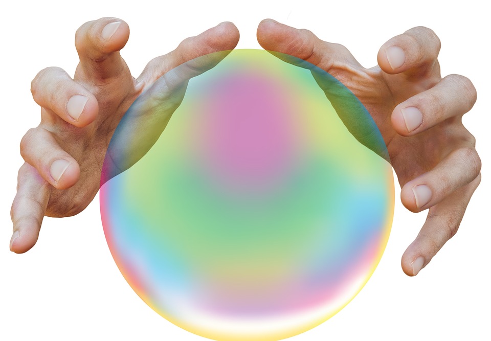 a pair of hands holding a rainbow colored sphere