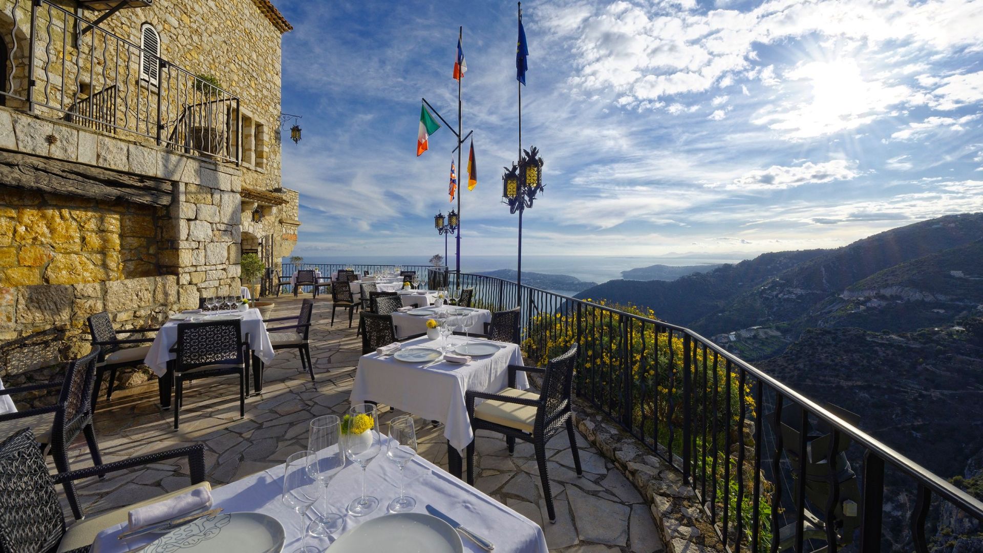 a restaurant with tables and chairs on a patio overlooking a mountain