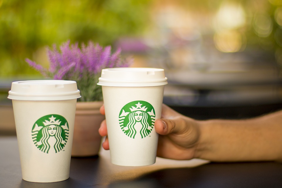 a hand holding two cups of coffee