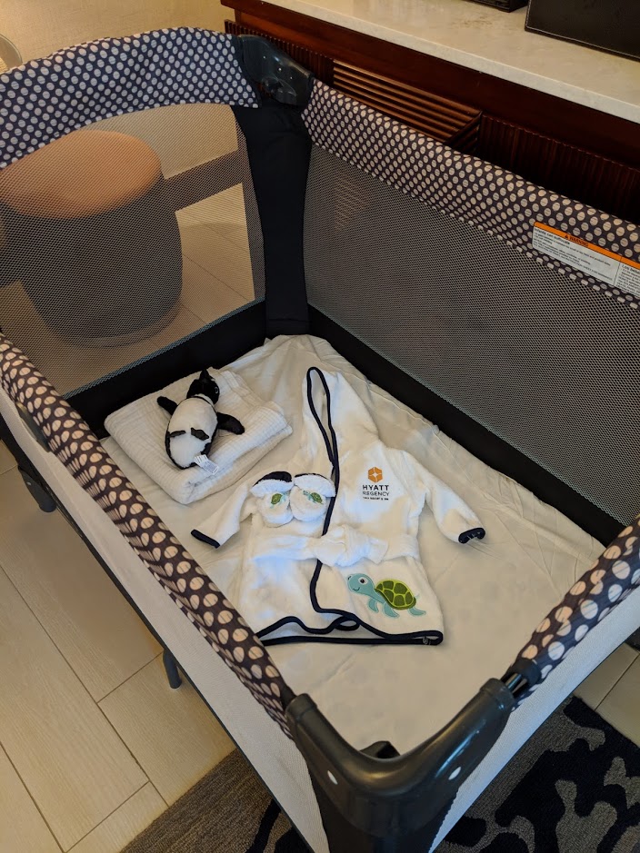 a baby cot with clothes and towels