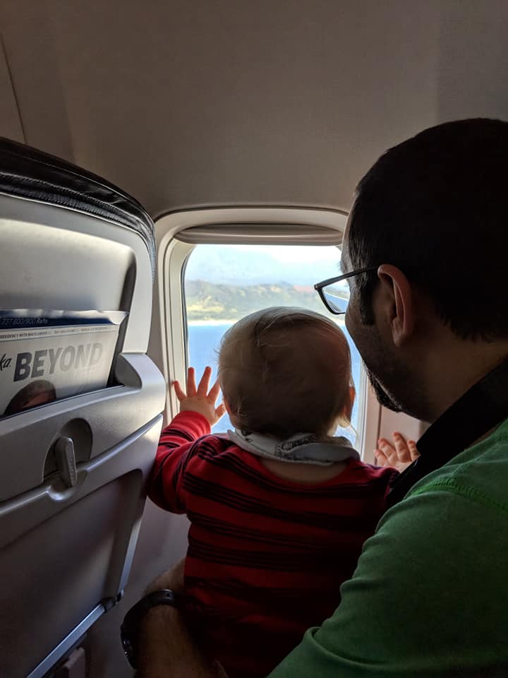 a man and baby looking out of an airplane window