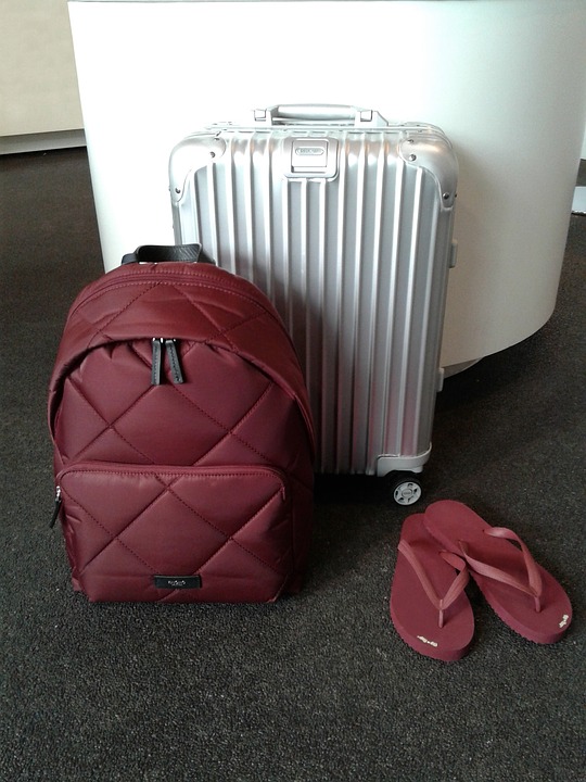a suitcase and flip flops next to a white cylinder