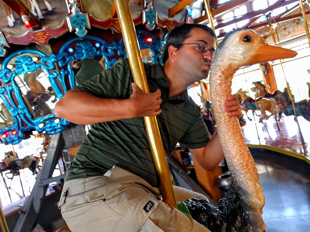 a man riding a carousel with a duck on it