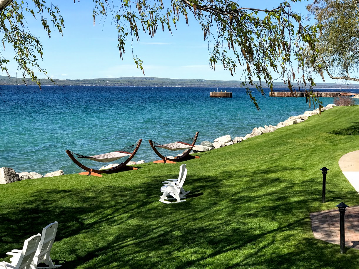 a lawn with chairs and hammocks on the side of the water
