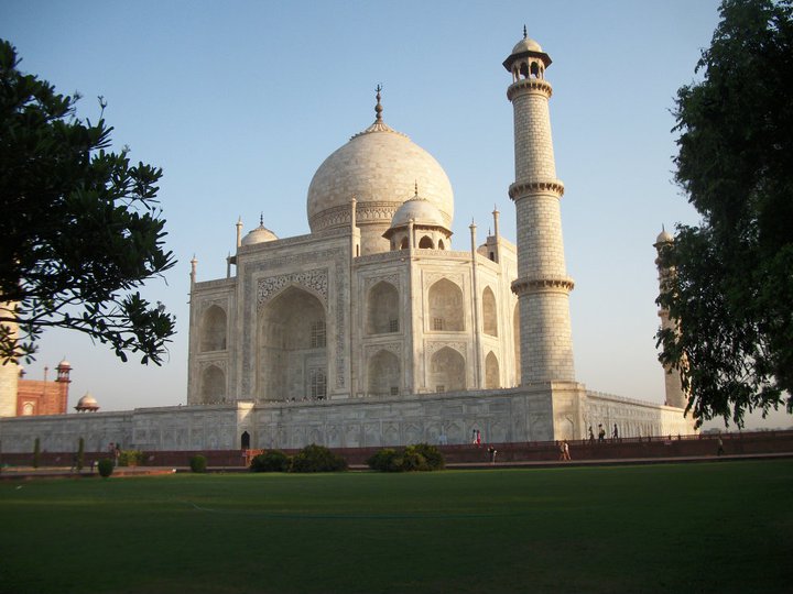 a large white building with domes and towers with Taj Mahal in the background