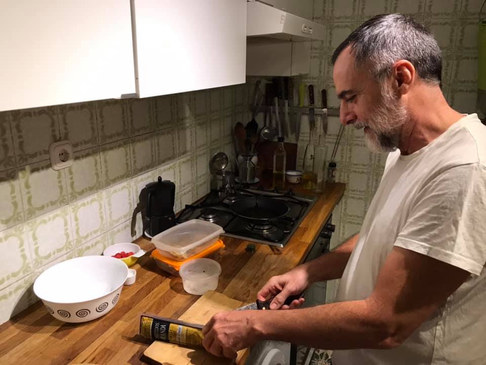 a man in a white shirt cutting food in a kitchen