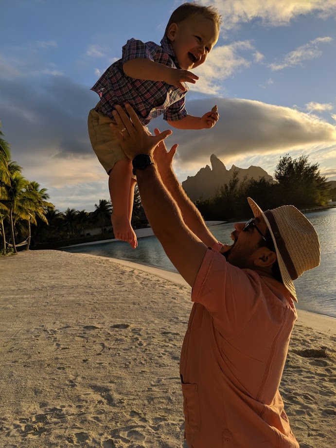 a man throwing a baby up in the air on a beach