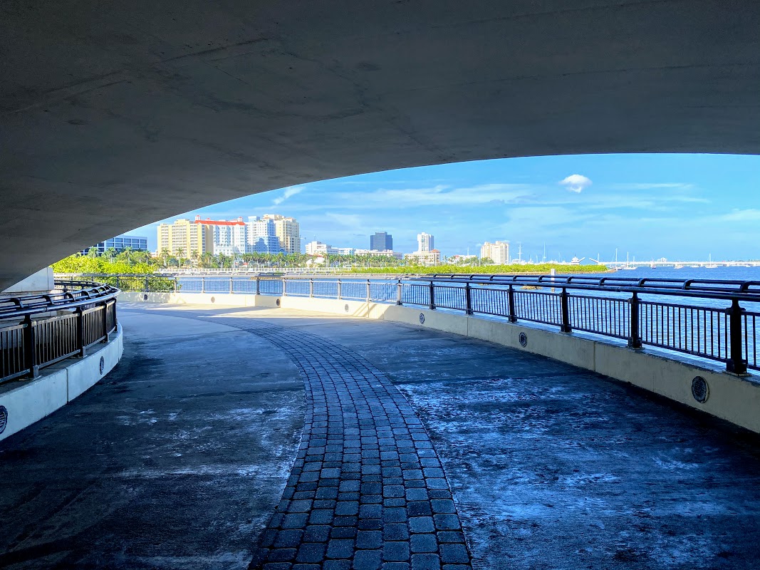 a walkway with a bridge over water and a city in the background