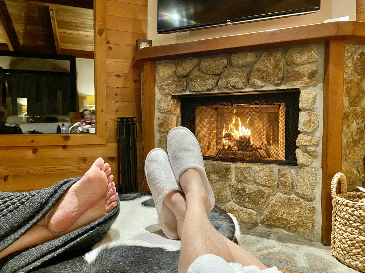 a pair of feet in slippers by a fireplace