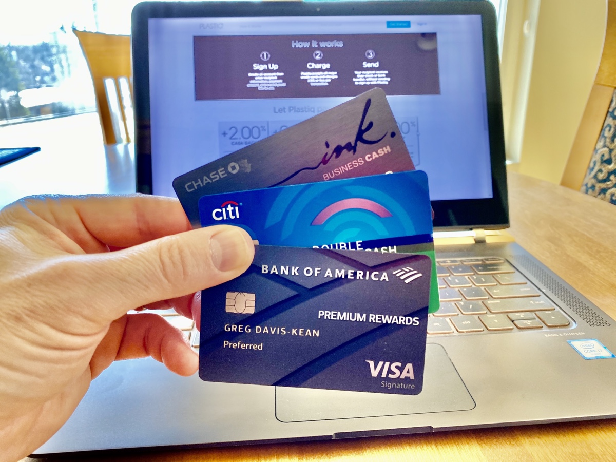 a hand holding credit cards in front of a laptop