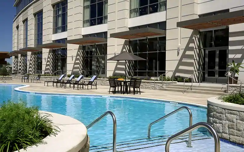 a pool with chairs and a table in front of a building