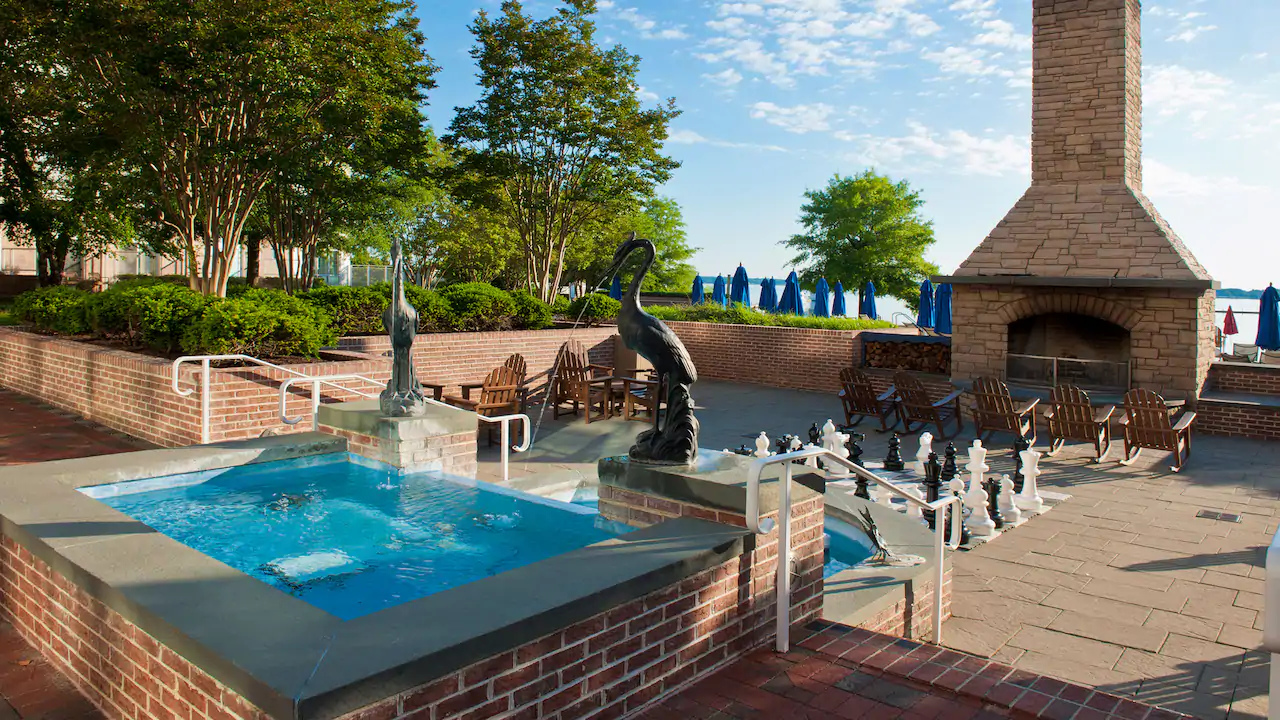 a fountain with a bird statue in the middle of a brick courtyard