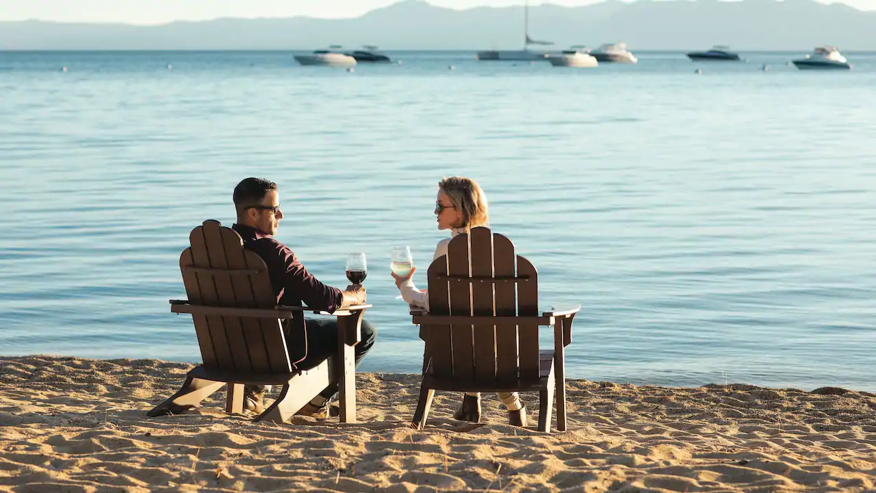 a man and woman sitting at chairs on a beach