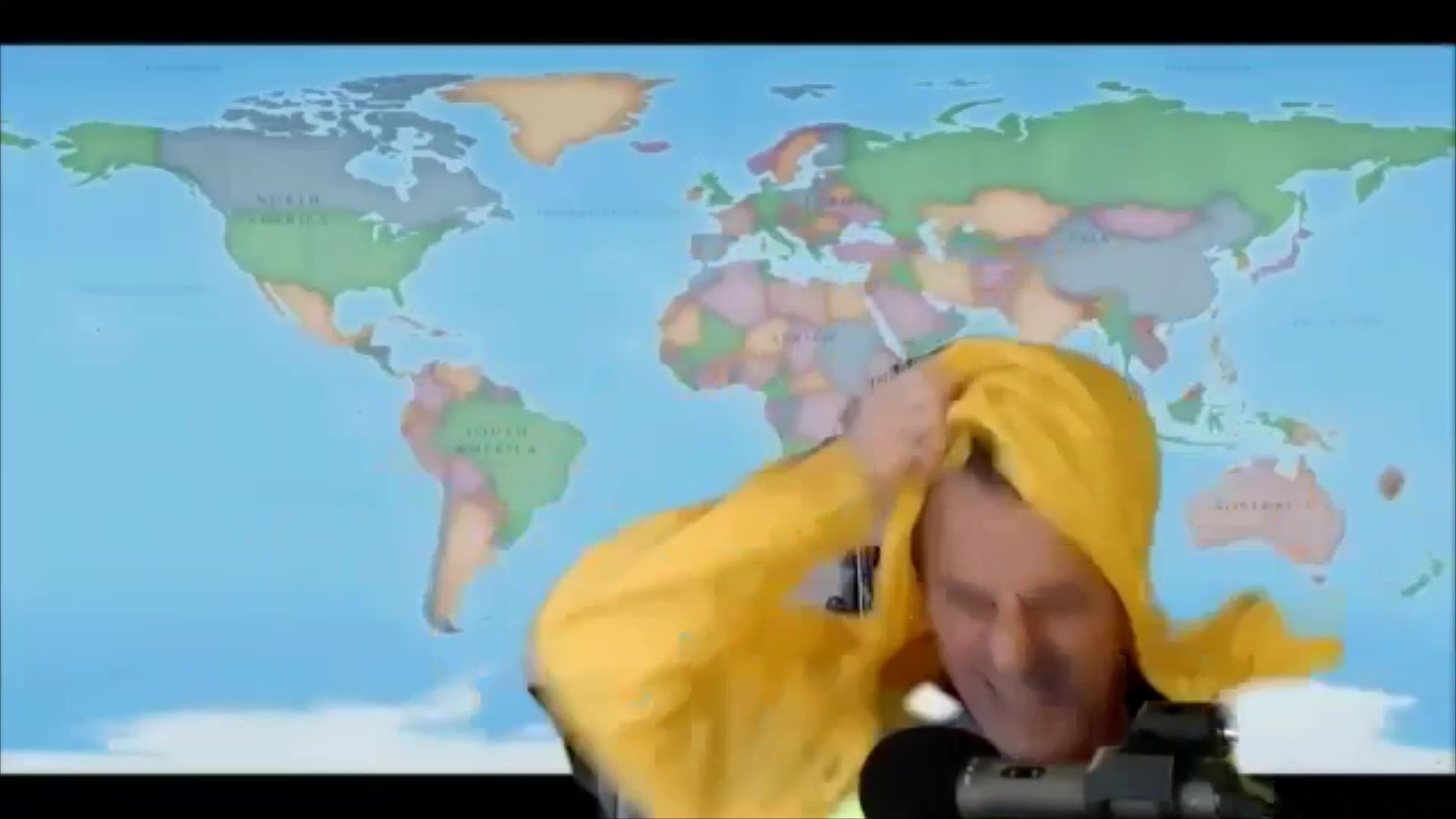a man in a yellow hoodie with a map behind him