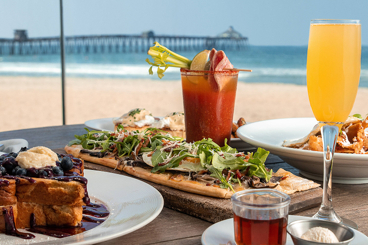 a table with plates of food and drinks on the beach
