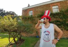 a man wearing a red white and blue hat and drinking from a cup