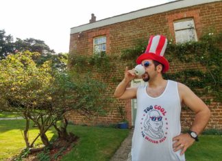 a man wearing a red white and blue hat and drinking from a cup