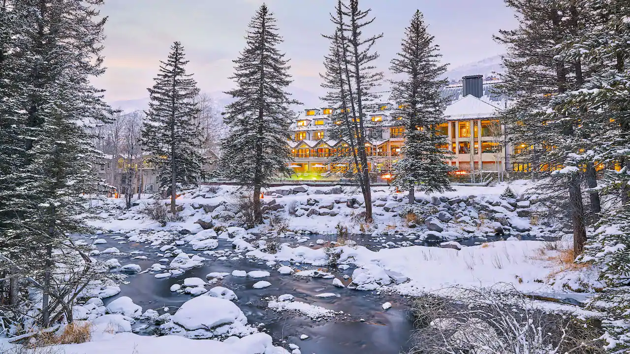 a river with snow and trees and a building
