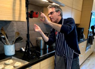 a man in a kitchen taking a picture of food