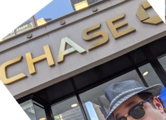 a man in a hat and sunglasses outside of a bank